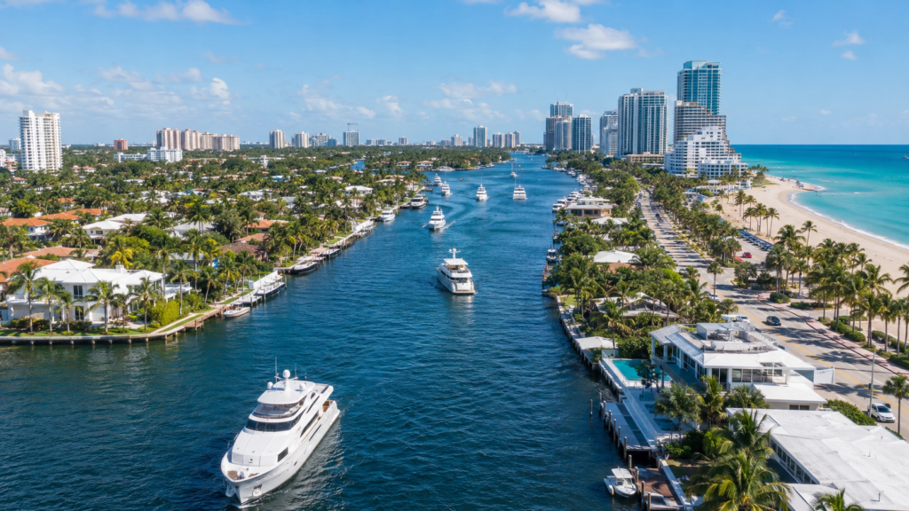 Aerial view of Broward County coastal neighborhoods with waterfront homes, yachts, beachfront towers, and the Atlantic Ocean.