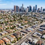 The architectural diversity across the Los Angeles metropolitan area, highlighting the contrast between residential neighborhoods and dense commercial districts. The intricate details of various real estate types and local businesses integrated into the urban landscape. The distinct textures of the cityscape, using bright, natural lighting to define the sprawling layout and the transitions between different zones of the city.