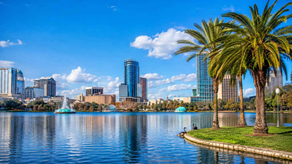 Orlando skyline in Orange County viewed across Lake Eola with palm trees, fountain, and downtown high-rise buildings.