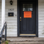 The front door of a single family home with a code violation notice on the door.
