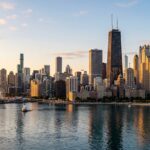 Photorealistic Chicago skyline with detailed architectural textures on the skyscrapers and glass facades. The scene is set during a clear golden hour, with warm, directional sunlight casting soft shadows and highlighting the city's silhouette. The surrounding water features natural ripples and clear reflections of the buildings and the gradient of the sky.