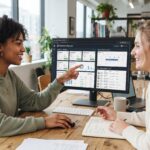 Two young female Gen Z real estate investors working together in a modern workspace, focused on a digital tracking system displayed on their screens that organizes property records, follow-up schedules, and lists of motivated seller leads through a clean, data-driven dashboard. On the dashboard we can see the URL ForeclosureFlips.com