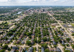 A distant aerial perspective of the Rockford, Illinois housing landscape, showcasing a vast expanse of residential neighborhoods with diverse architectural styles, tree-lined avenues, and a dense arrangement of suburban rooftops sprawling across the Midwestern terrain.
