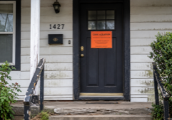The front door of a single family home with a code violation notice on the door.