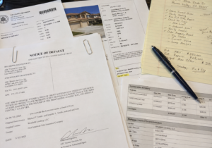 a close-up of foreclosure public records, notice of default documents, and property research notes